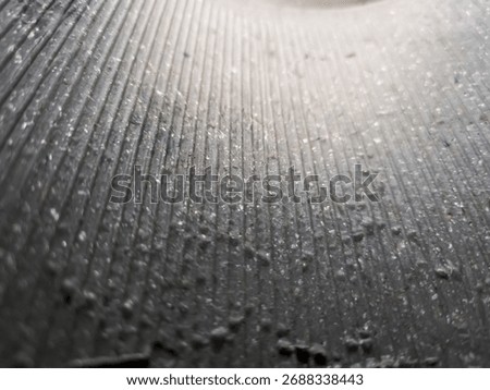 Close-up of abstract surface with vertical ridges and scattered dust particles. Ideal for texture studies, industrial design, or minimalist backgrounds.
