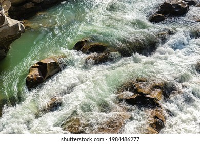 Close-up abstract texture above view of river torrent and clear fresh cold water flowing through mountain rocks in valley with foam and bubbles on sunny day. Nature force and power background - Shutterstock ID 1984486277