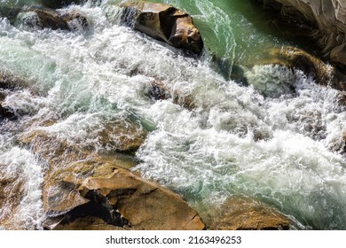 Close-up abstract texture above view of river torrent and clear fresh cold water flowing through mountain rocks in valley with foam and bubbles on sunny day. Nature force and power background - Powered by Shutterstock