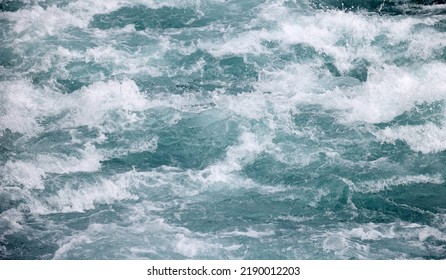 Close-up Abstract Texture Above View Of River Torrent And Clear Fresh Cold Water Flowing Through Mountain Rocks In Valley With Foam And Bubbles On Sunny Day. Nature Force And Power Background