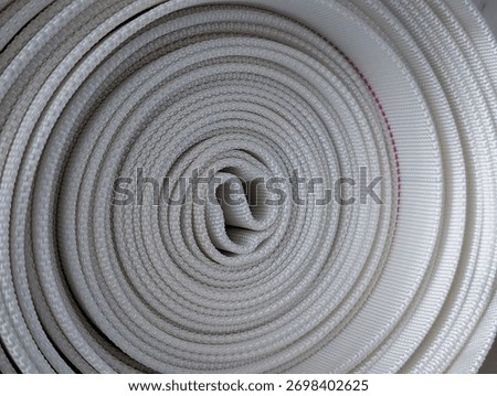close-up abstract texture of white coiled fire hose for safety and industrial concepts
