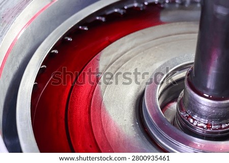 Close-up abstract view of internal automatic transmission gear components partially submerged in clean red ATF fluid inside the housing during service.