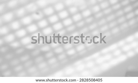 A close-up abstract view of light and shadow creating a geometric pattern on a white background, suggesting texture and depth.