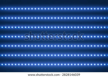 A close-up, abstract view of multiple parallel blue LED light strips creating a vibrant, glowing pattern.