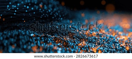 A close-up, abstract view of numerous small, glowing particles in shades of blue and orange, creating a dynamic and energetic visual effect.