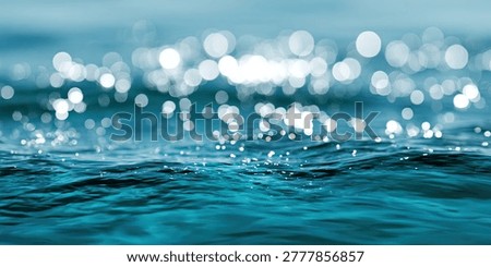 A close-up, abstract view of the ocean's surface, with shimmering bokeh lights reflecting on the turquoise water.