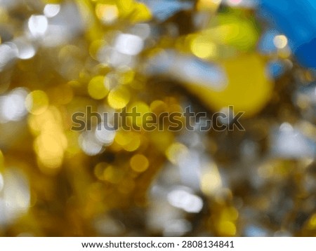 A close-up, abstract view of out-of-focus lights, creating a bokeh effect with shimmering gold, silver, and hints of blue.