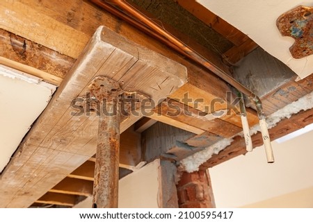 Close-up of an acrow prop supporting exposed wooden floor joists at renovated house.