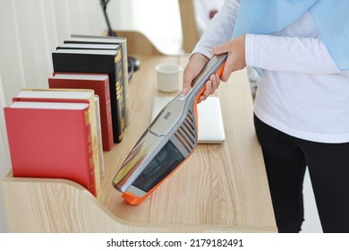 Closeup Active Young Asian Muslim Housewife Woman Hands Cleaning With Vacuum Cleaning Wooden Table With Computer Blurred Background. Cleaning Girl In White Dress And Black Leggings Vacuuming Her Room