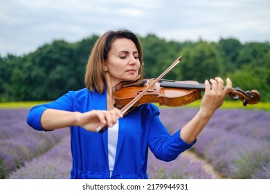 Close-up Adult Caucasian Woman Violinist Playing Violin On Summer Lavender Field, Romantic Musician In Blue Dress Enjoying Walking On Nature