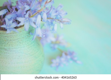 Closeup Aerial of Dreamy Pastel Lavender Lilly Flowers Spilling out of a Green Stoneware Vase with a Teal Blue Horizontal Wood Background with room or space for copy, text, your words to the side