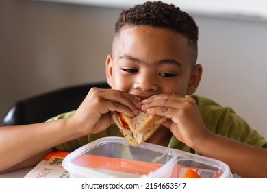 Close-up of african american elementary schoolboy eating sandwich at desk during lunch break. unaltered, education, childhood, break, food and school concept. - Powered by Shutterstock