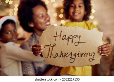 Close-up Of African American Family Holding Happy Thanksgiving Sign While Celebrating At Home.