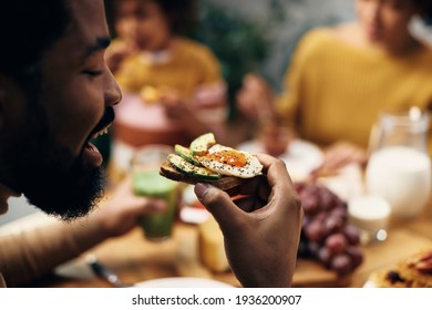 Close-up Of African American Man Eating Sandwich With Avocado And Eggs. 