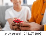 Closeup, African American man playing with his son, holding small red car toy, selective focus on his hands. Childhood concept