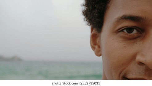 Close-up of African American man standing on the beach. He is smiling and looking at camera - Powered by Shutterstock