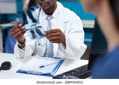 Closeup of african american pediatrician doctor holding lungs radiography explaining xray expertise to patient mother discussing medical treatment in hospital office. Health care service - Powered by Shutterstock