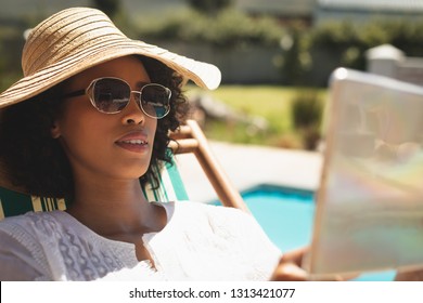 Close-up Of African American Woman With Hat And Sunglasses Using Digital Tablet In Her Backyard On A Sunny Day