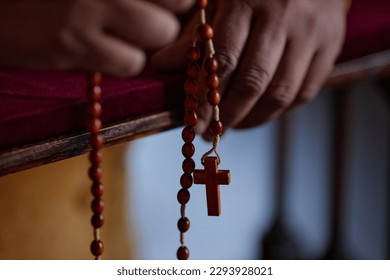 Close-up of African American woman holding rosary beads while reading prayer in church - Powered by Shutterstock