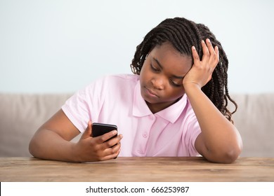 Close-up Of An African Bored Girl Looking At Cell Phone