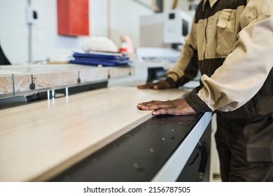 Close-up Of African Craftsman Sawing Wooden Plank On Machine During Work At Furniture Factory