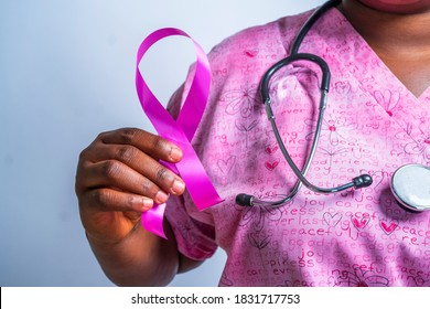 Closeup of an African descent hands holding a pink ribbon with stethoscope around neck-concept on breast cancer awareness