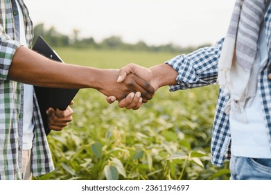 Close-up of African farmers shaking hands on the background of a soybean field - Powered by Shutterstock