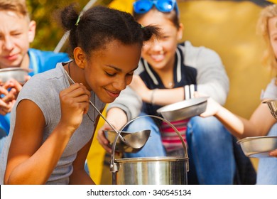 Close-up of African girl cooking soup at campsite - Powered by Shutterstock