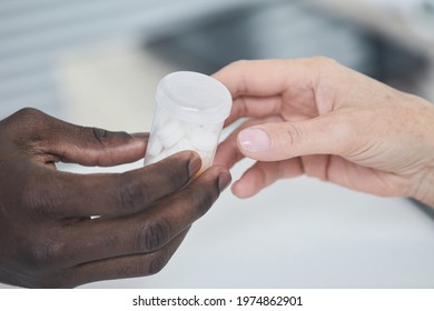 Close-up Of African Man Giving Bottle With Medicine To Woman