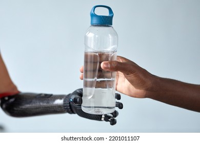 Close-up Of African Man Giving Bottle Of Water To Woman With Prosthetic Arm Isolated On Blue Background