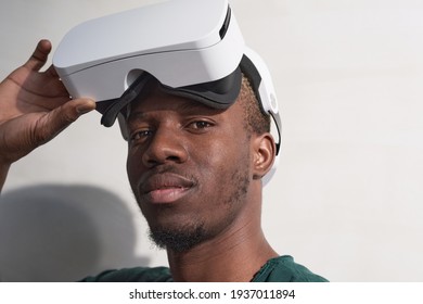 Close-up of African man putting on vr glasses looking at camera isolated on white background