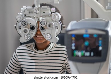 Close-up Of african teen girl Doing Eye Test On Phoropter, African teen girl checking on her eye with optometry machine. - Powered by Shutterstock