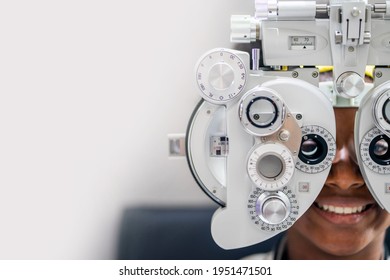 Close-up Of african teen girl Doing Eye Test On Phoropter, African teen girl checking on her eye with optometry machine. copy space background for text