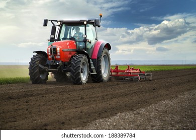 Close-up of agriculture red tractor cultivating field over blue sky - Powered by Shutterstock