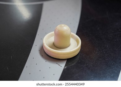 Close-up of an air hockey puck on a table. Ready for action. A Game of Skill and Fun of Air Hockey Puck Close-Up. - Powered by Shutterstock