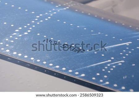 Close-up of airplane wing surface with warning and rivet details visible during bright daylight conditions