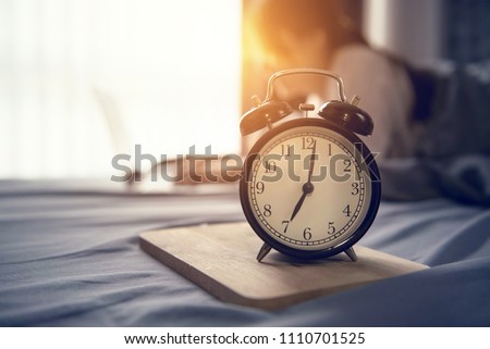 Closeup alarm clock, Business woman wake up and working with laptop computer on bed in morning, start new project concept ストックフォト © 