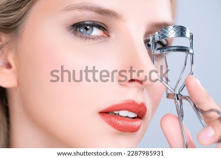 Closeup alluring facial makeup, beautiful woman with perfect smooth cosmetic clean skin correct eyelash curler with metal mechanic beauty accessory in isolated background.