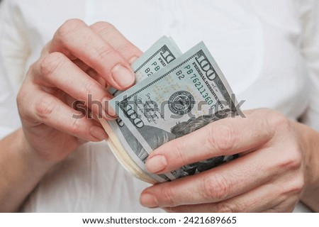 Close-up of American dollars in hands, counting banknotes, light background. Concept of finance, business, income.