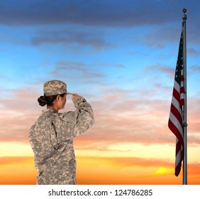 Closeup of an American Female Soldier in combat uniform saluting a flag at sunset.