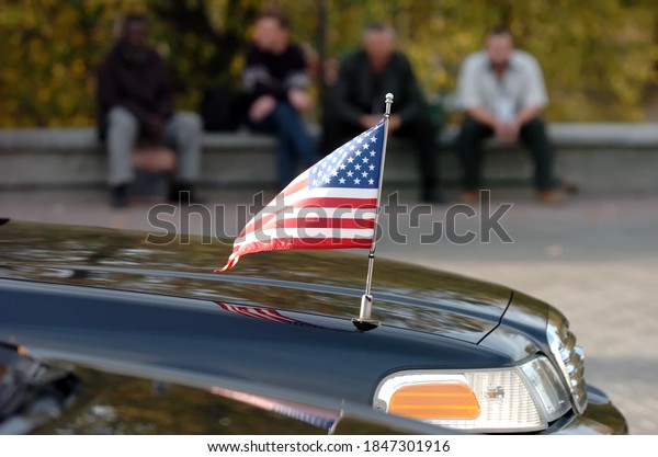 Closeup of American flag attached to car.\
people in the\
background