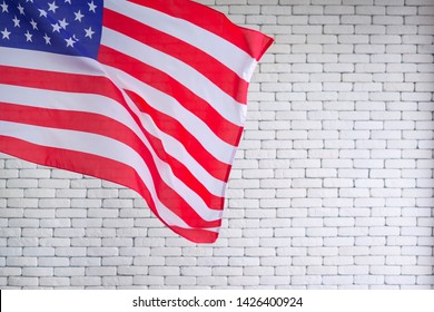 Close-up of the American flag is placed on the left side with copy space on a white brick wall background. 4th of July. Celebrate American National Day. Labor Day. Independence Day. Memorial Day.