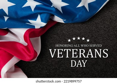 Closeup of American flag with Text Veterans Day Honoring All Who Served on black textured background. American holiday banner.