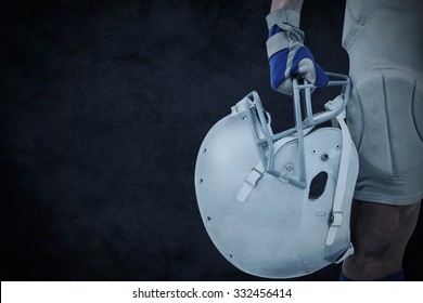 Close-up Of American Football Player Holding Helmet Against Grey Background