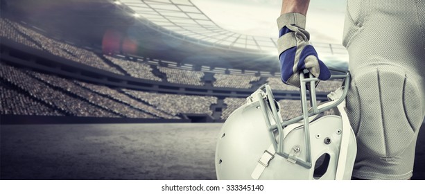 Close-up of American football player holding helmet against rugby stadium - Powered by Shutterstock