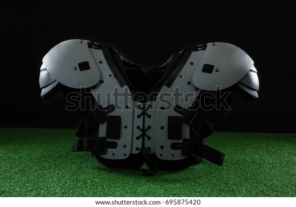 Close-up of American football shoulder pads over\
artificial turf