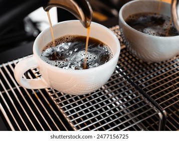 Close-up of Americano pouring from the coffee machine into a cup. Professional coffee brewing black coffee