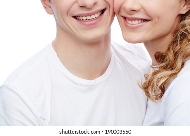 Close-up of amorous young couple in white T-shirts with toothy smiles