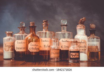 Closeup Of Ancient Apothecary Pots With Ingredients For Medicine Isolated Over Dark Background. Translation : Terpine Powder, Drosera And Aubepine Tincture, Kola Tincture, Iris Essential Oil, Morphine