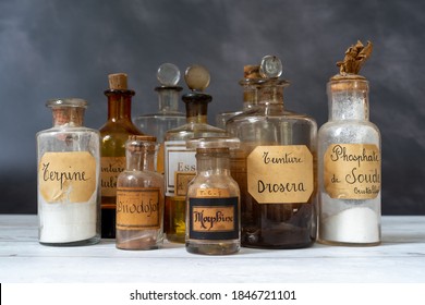 Closeup Of Ancient Apothecary Pots With Ingredients For Medicine Isolated Over Dark Background. Translation : Terpine Powder, Drosera And Aubepine Tincture, Kola Tincture, Iris Essential Oil, Morphine